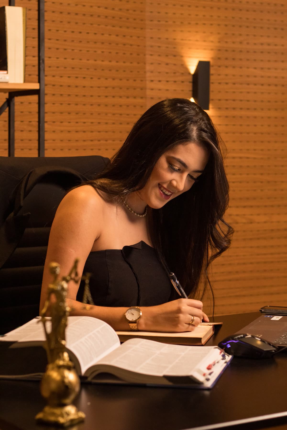 Lígia escrevendo à mesa do escritório, com um código aberto